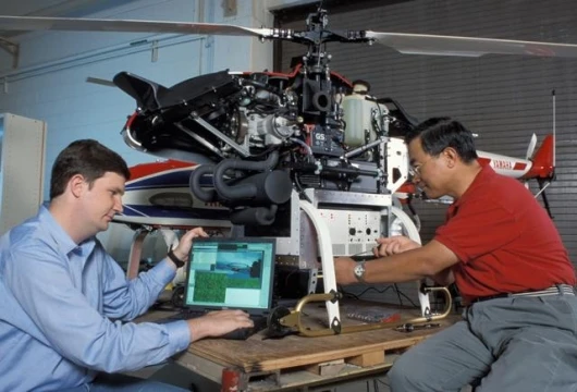 Eric Johnson (l) and Jeong Hur adjust controls of the GTMAX test bed UAV helicopter.