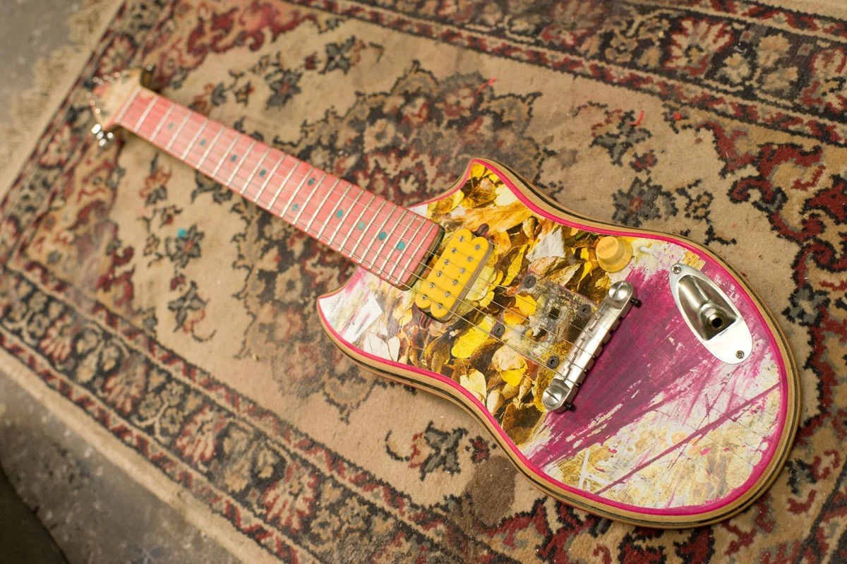 This colorful model features a fixed bridge, humbucking pickups, a single volume knob and externally-mounted audio connector