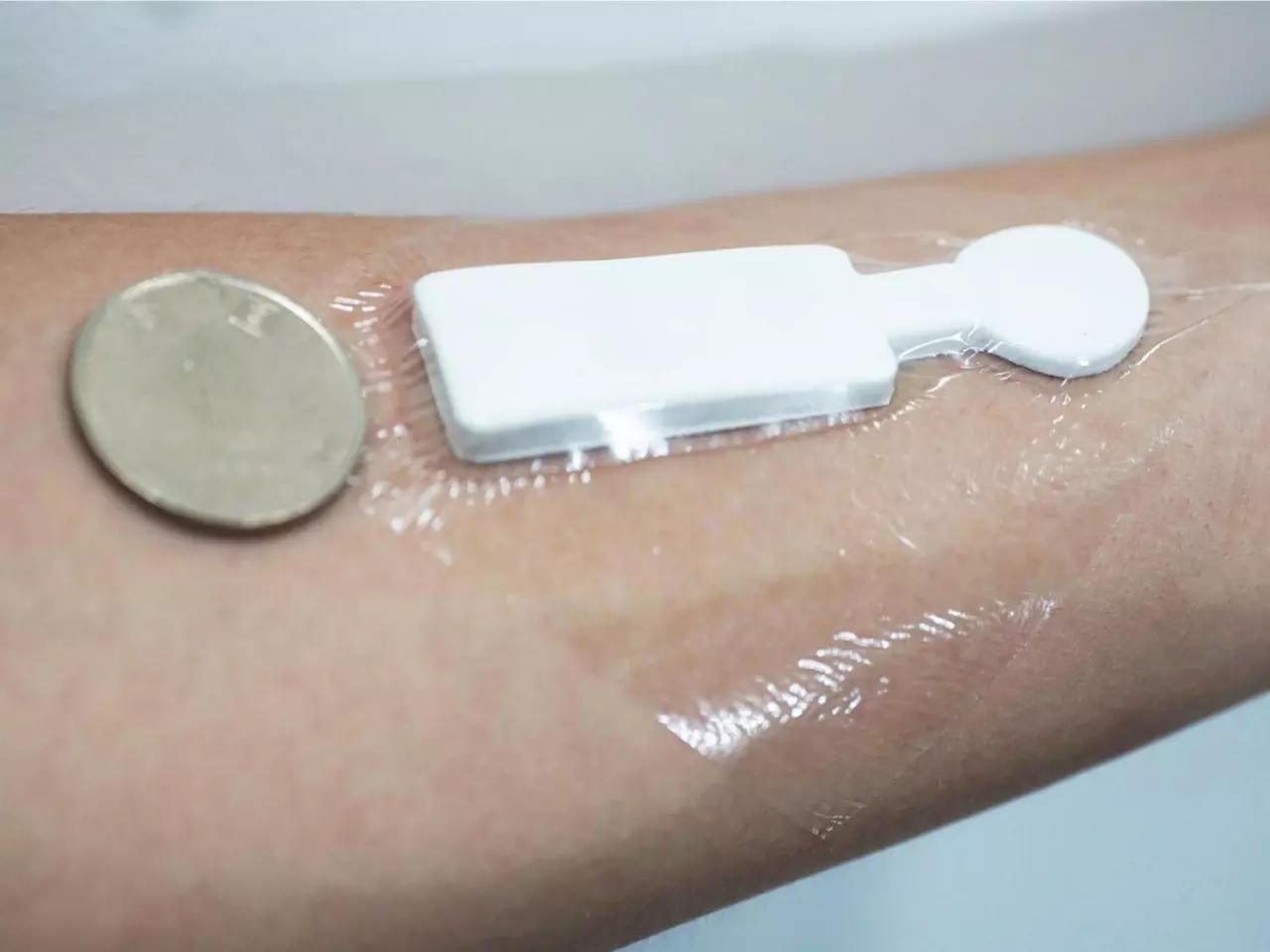 The temperature- and humidity-monitoring capabilities of the device (shown here with a US quarter-dollar coin for scale) were tested not only on volunteers' cheeks and foreheads, but also on their arms and fingertips