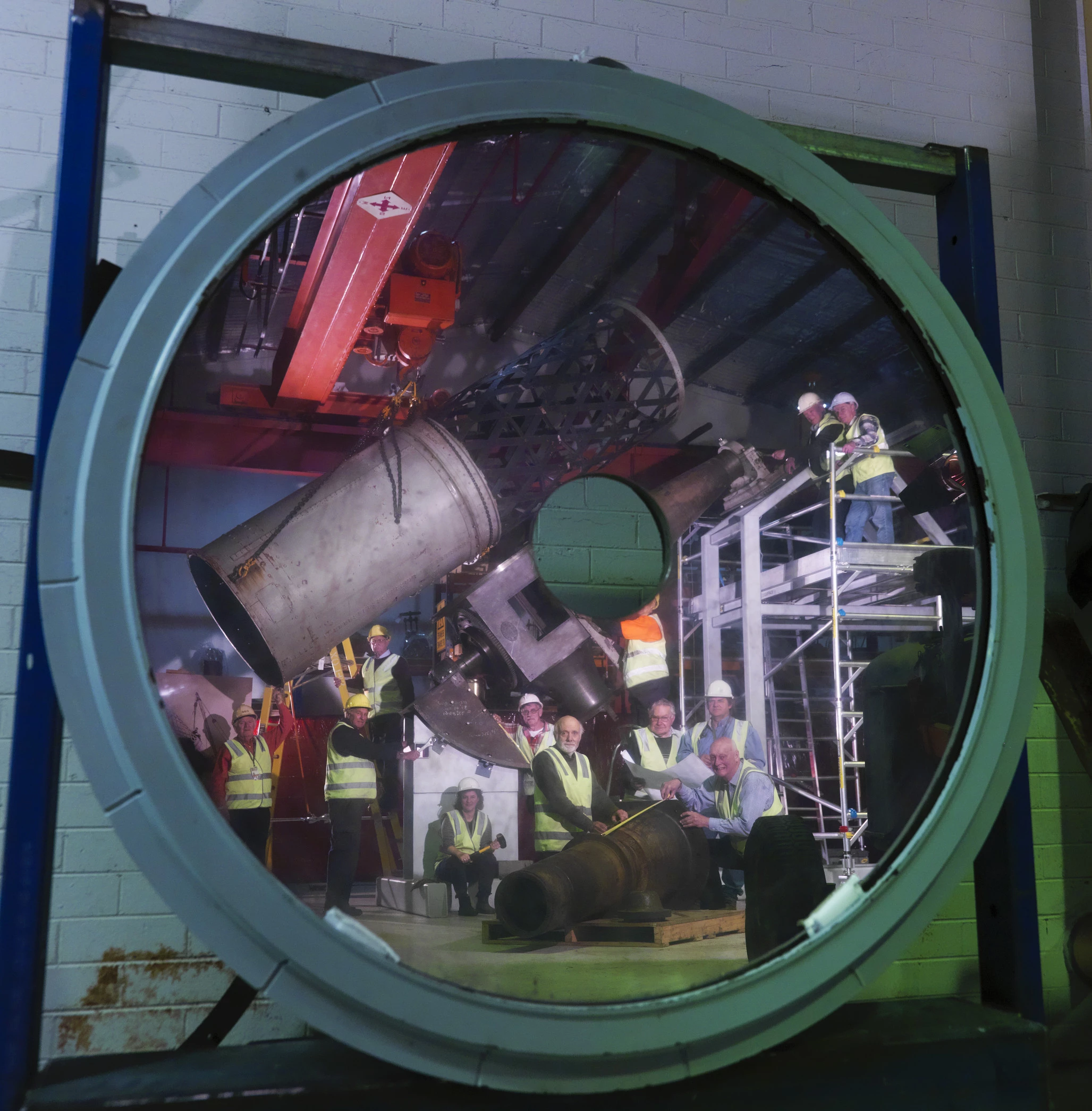 Volunteers and staff with components of the Great Melbourne Telescope reflected in the mirror of the original telescope