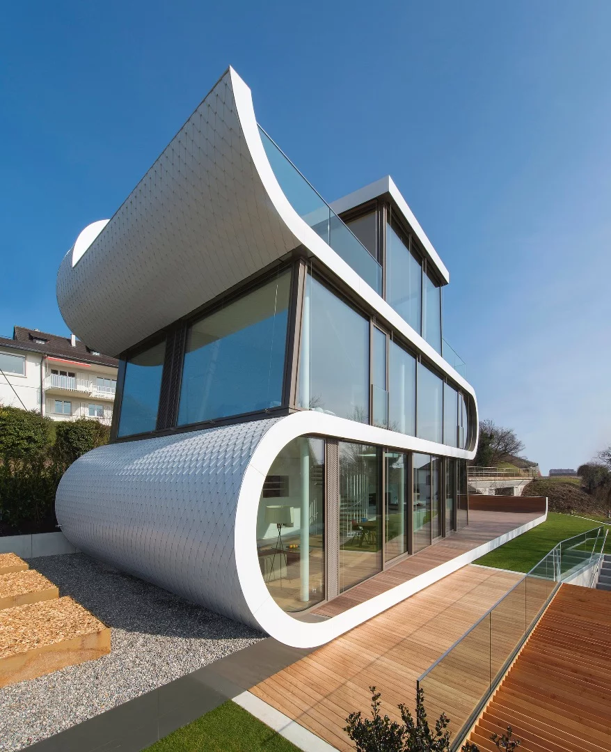 The ribbon-like white facade breaks up the glazing and gives the house its shape