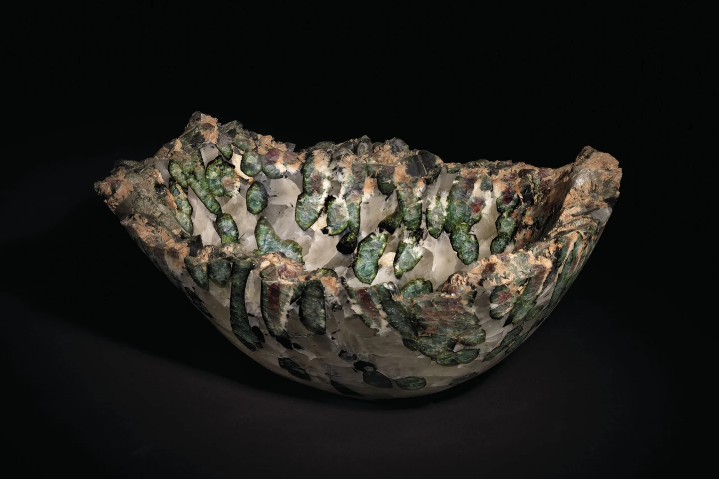 Originating in Brazil, this tourmaline bowl was created from a larger original specimen by polishing the interior and exterior to reveal cross-sections of large watermelon tourmaline crystals. The colours of the resultant 15 inch (38 cm) bowl range from black to purple, through greens and pinks, with the rim of the quartz matrix left in its original natural state.