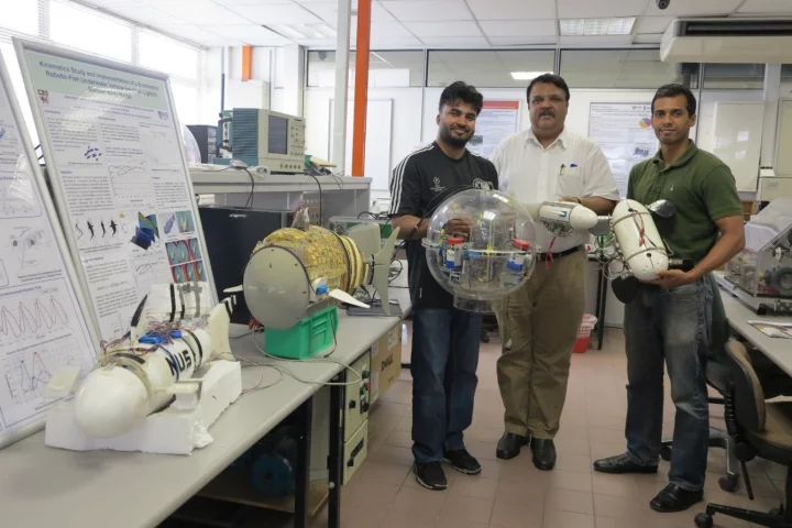 Bhuneshwar Prasad (left), Associate Professor S.K. Panda and Abhra Roy Chowdhury, holding the turtle robot at right (Photo: National University of Singapore)