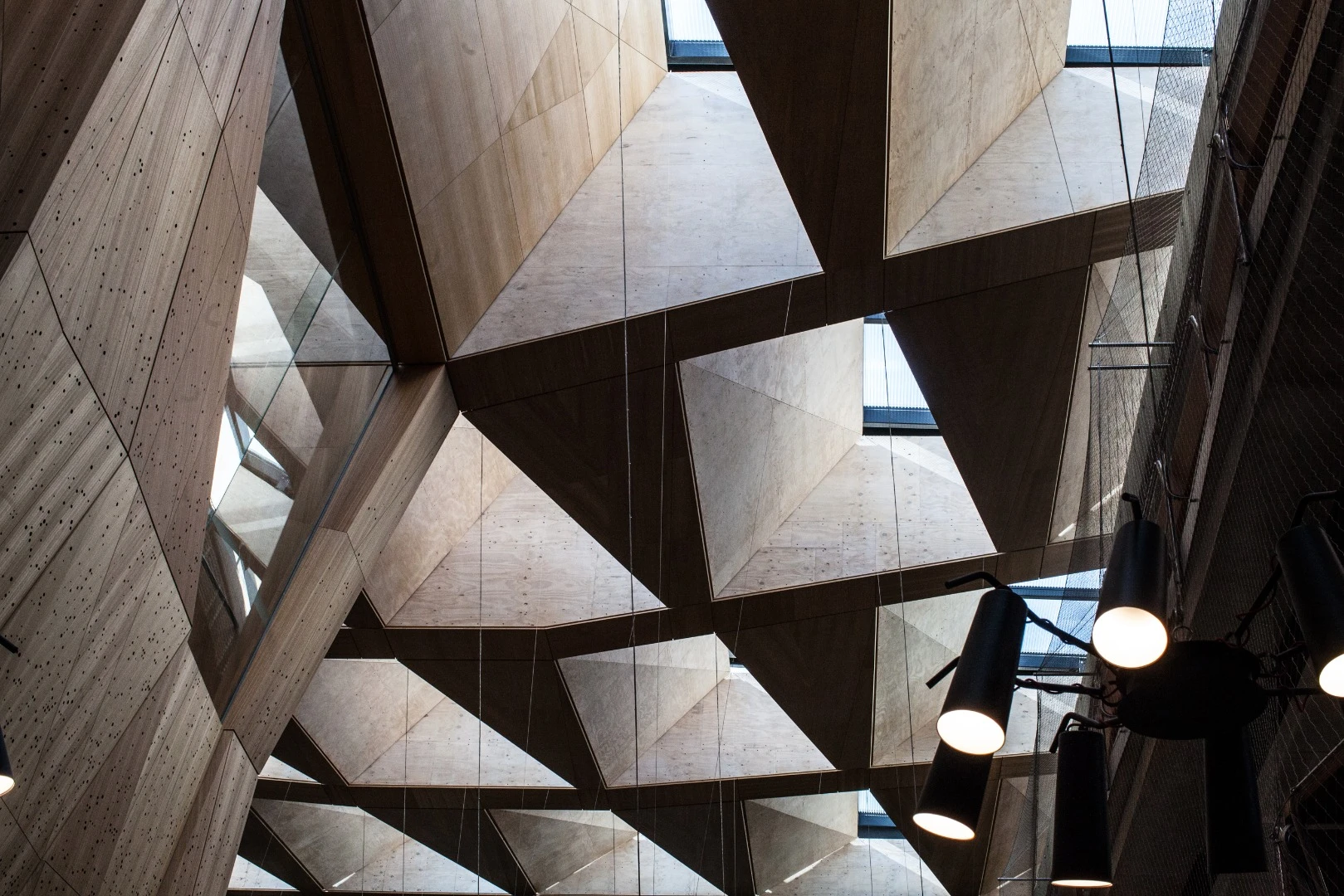Huge laminated plywood panels attached to the skylight to create a coffered ceiling, angled in such a way that they direct the sunlight to the floor