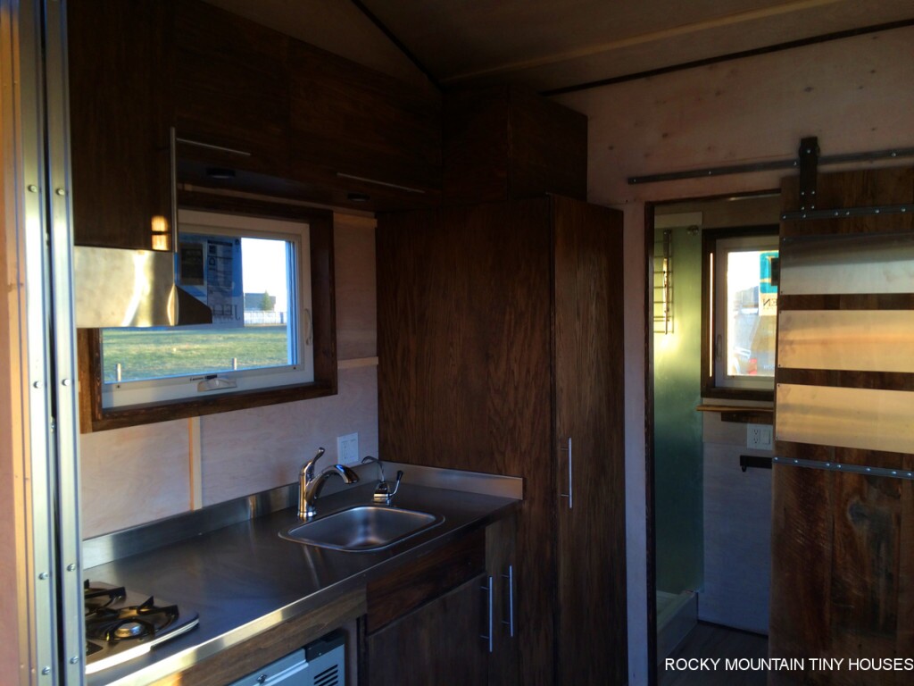 The kitchenette features a chest refrigerator, side pantry, a two-burner cooktop, and a folding dining table