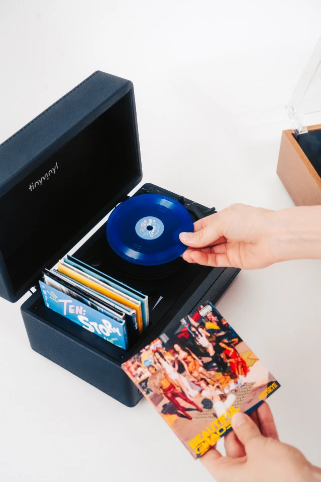 The Tiny Vinyl Player pairs a miniature belt-drive platter with built-in storage slots for holding a small selection of four-inch record sleeves