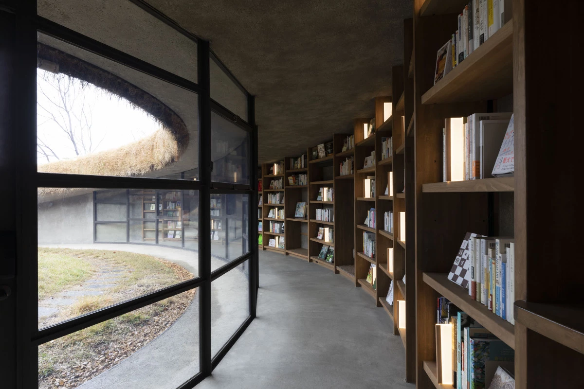 The library is encased by a curved glass wall and walkway, overlooking the central grassy courtyard