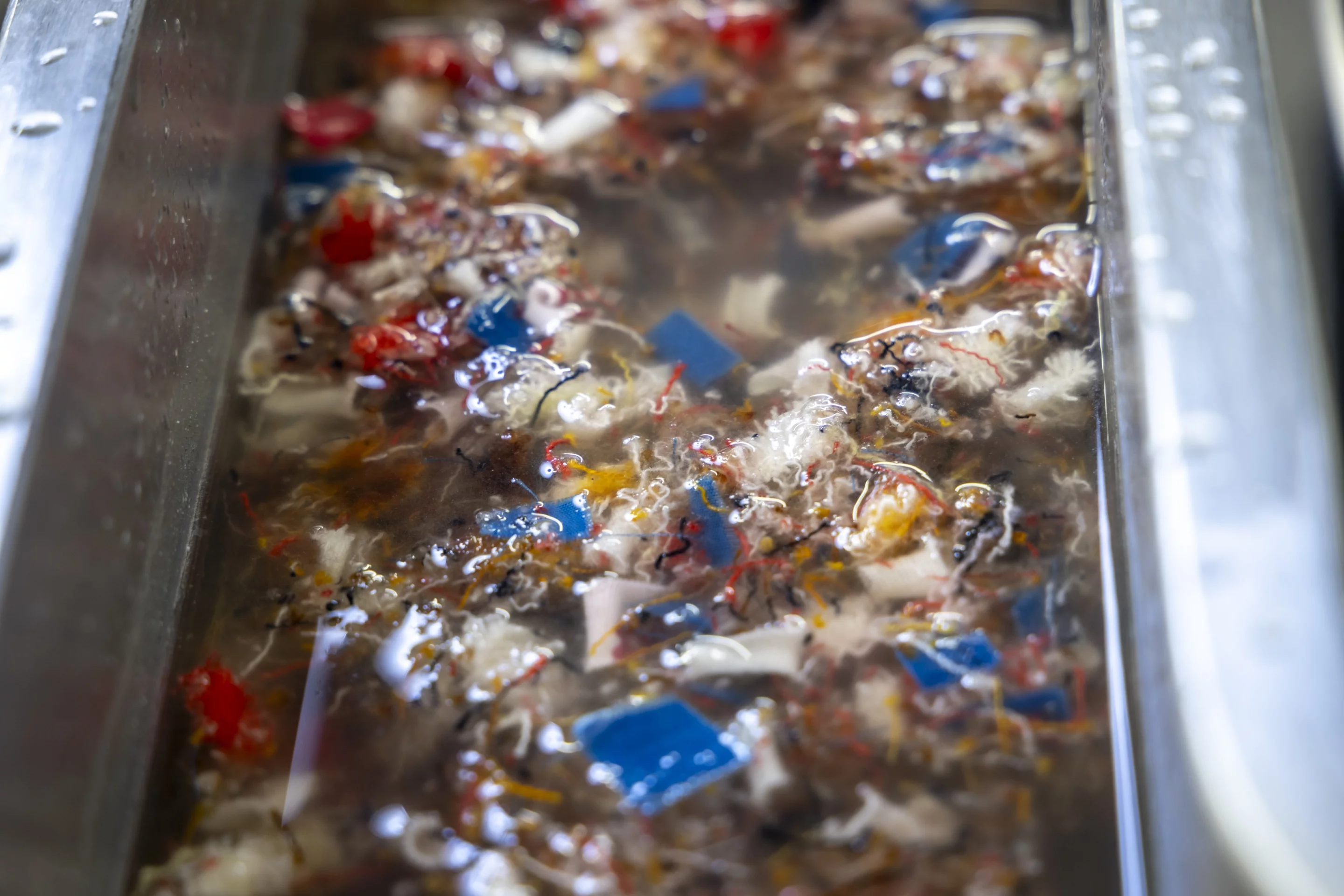 Shredded cotton clothing gets soaked in an aqueous solution prior to milling