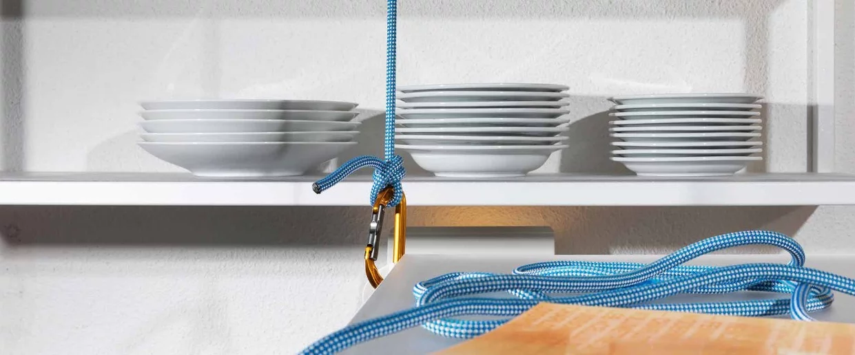 The architects installed a white dining table with a pulley system, allowing it to be lifted up towards the ceiling when not in use