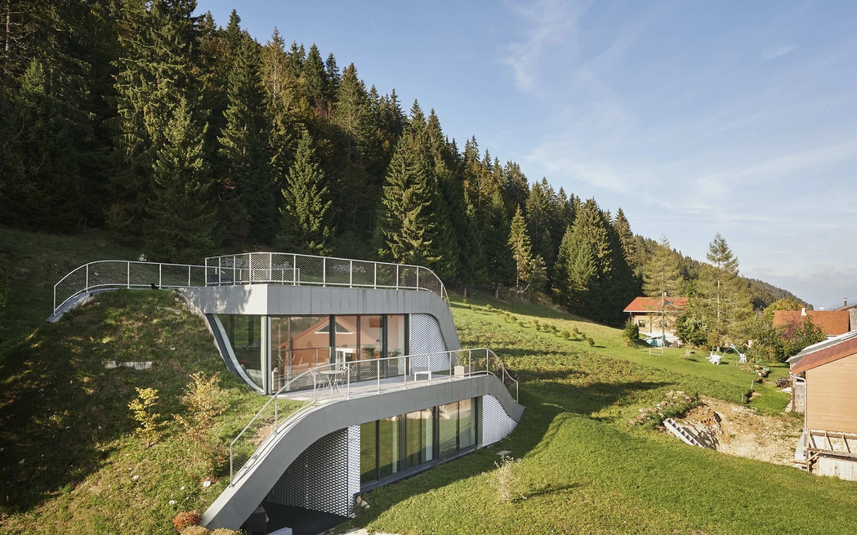In France sits Casa Jura, a residential home built into the surrounding hill leaving just a couple of small outcrops to allow light in