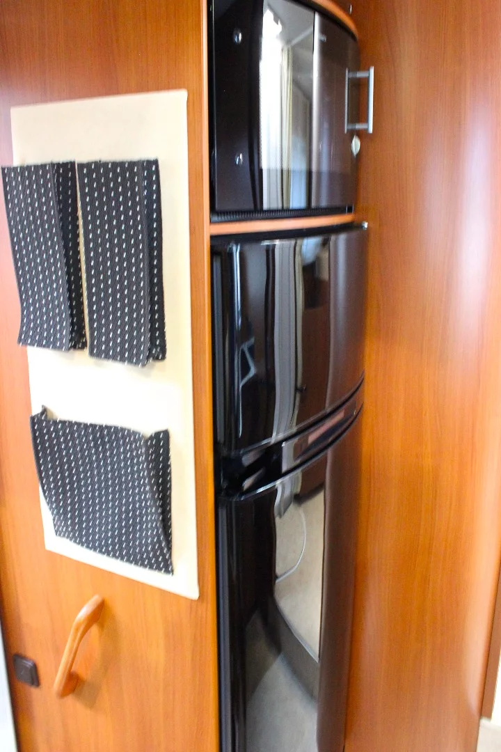 The refrigerator and oven are located across from the kitchen block