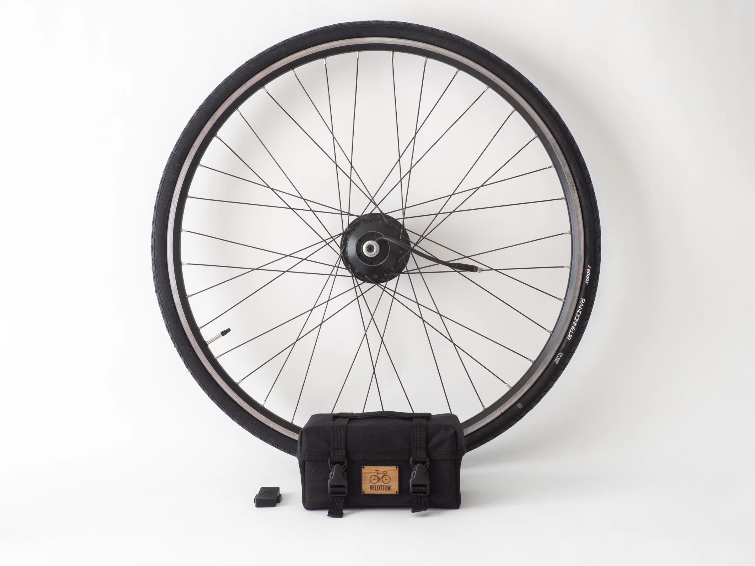 The basic Vekkit ebike conversion kit comprises a wheel rocking a hub motor, a bag that's home to the battery and electronics and a wireless cadence sensor for attaching to the pedal