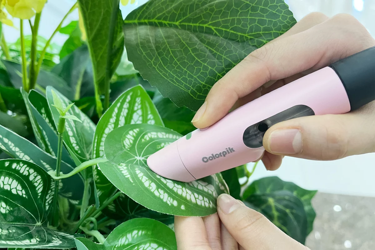 The Colorpik Pen scanning a leaf, so it can draw (or write) in leafy green