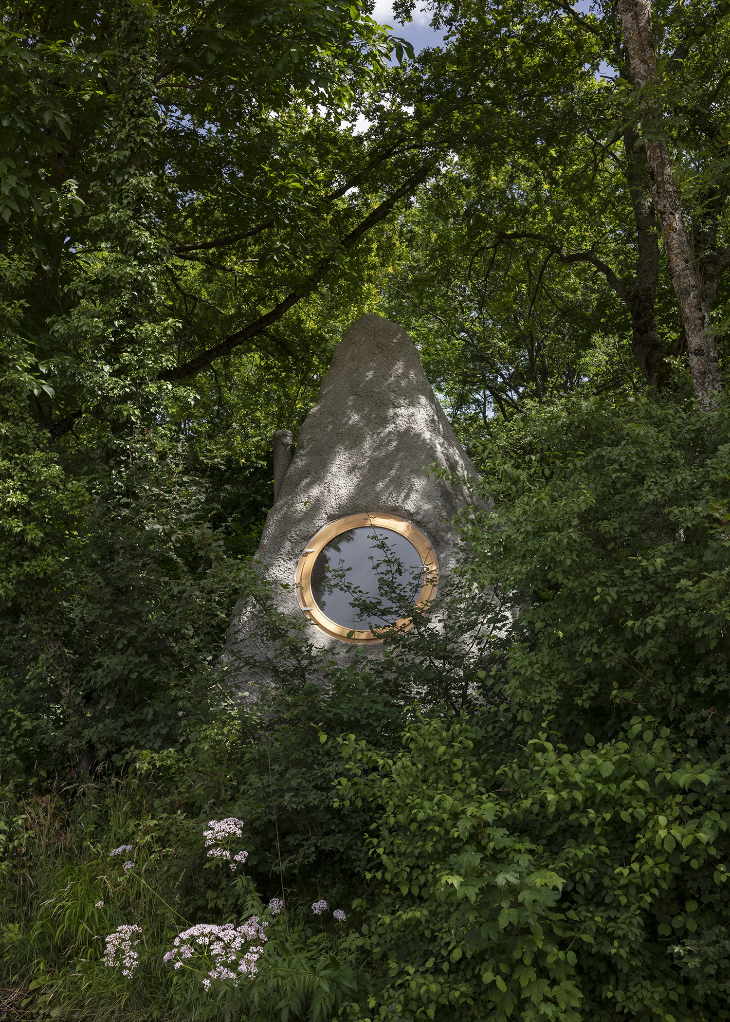 Thérèse is nestled into some trees and would be easy to mistake as a boulder from some angles, though its front-facing side has a large porthole-style window
