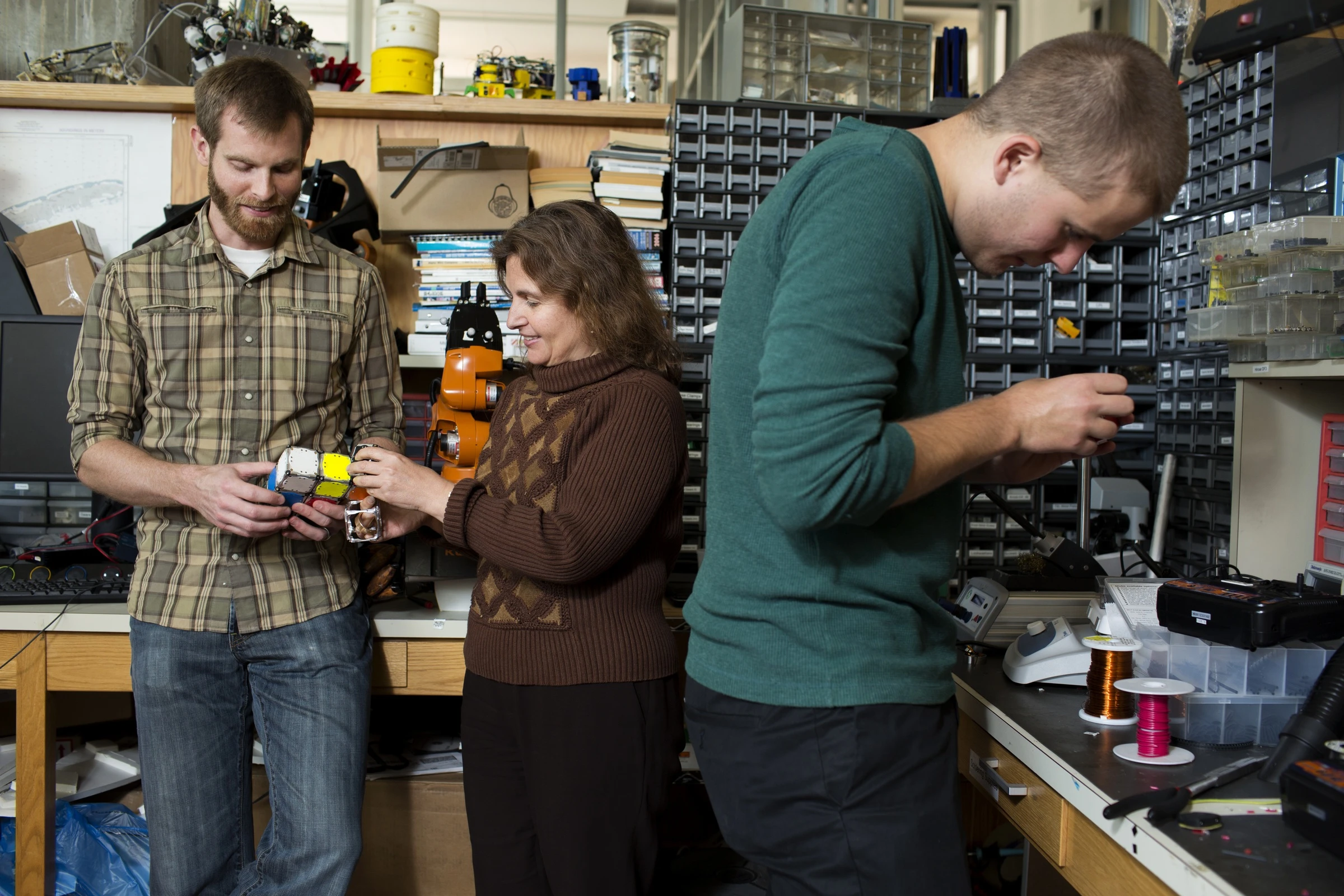 Postdoctoral associate Kyle Gilpin (left), Professor of Electrical Engineering and Computer Science Daniela Rus (center), and and robotics engineer John Romanishin (right) working with the M-Blocks (Photo: M. Scott Brauer)