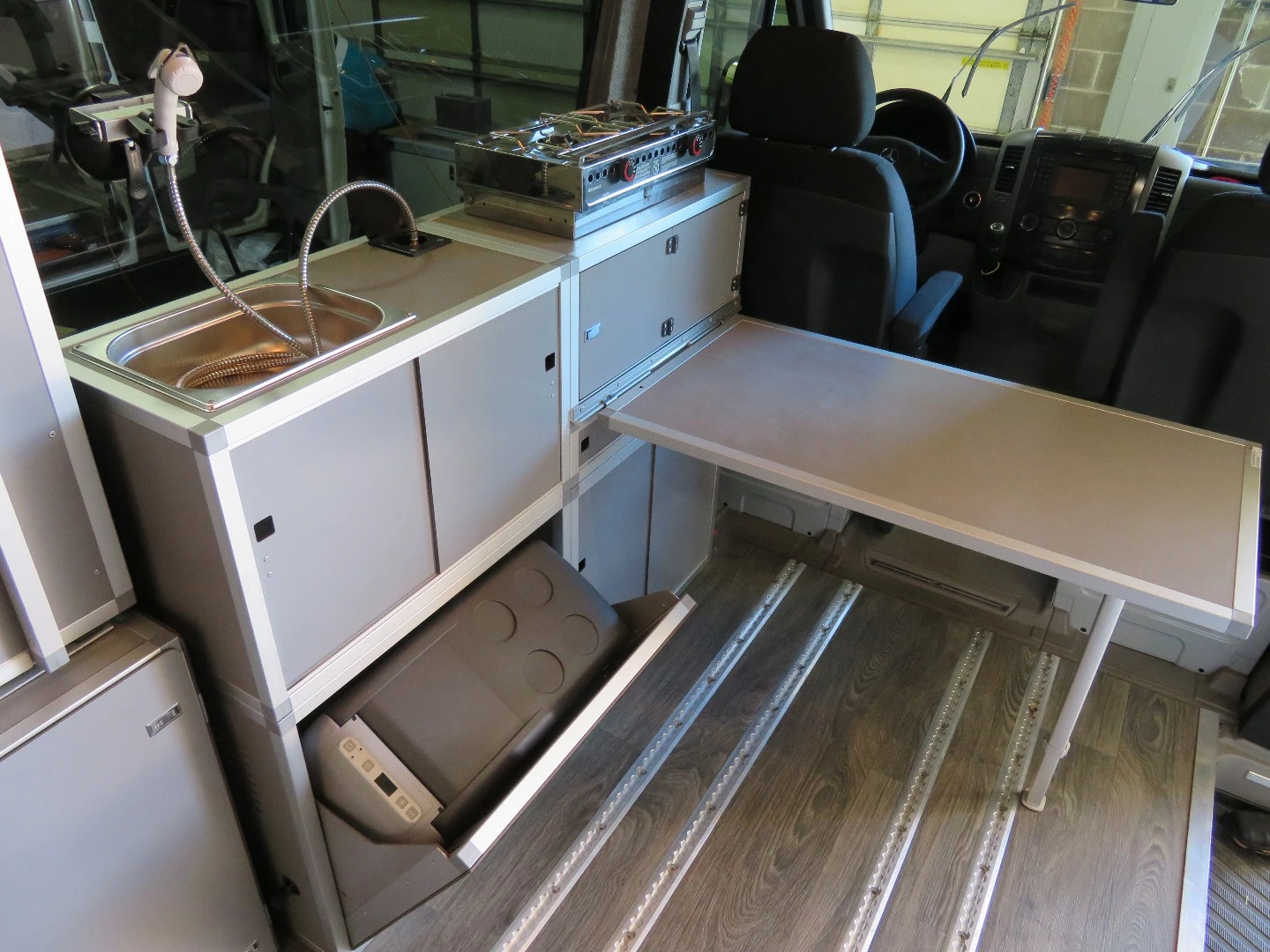 The Terracamper Sprinter's refrigerator/freezer tilts out from the bottom, and a removable table creates a dining space