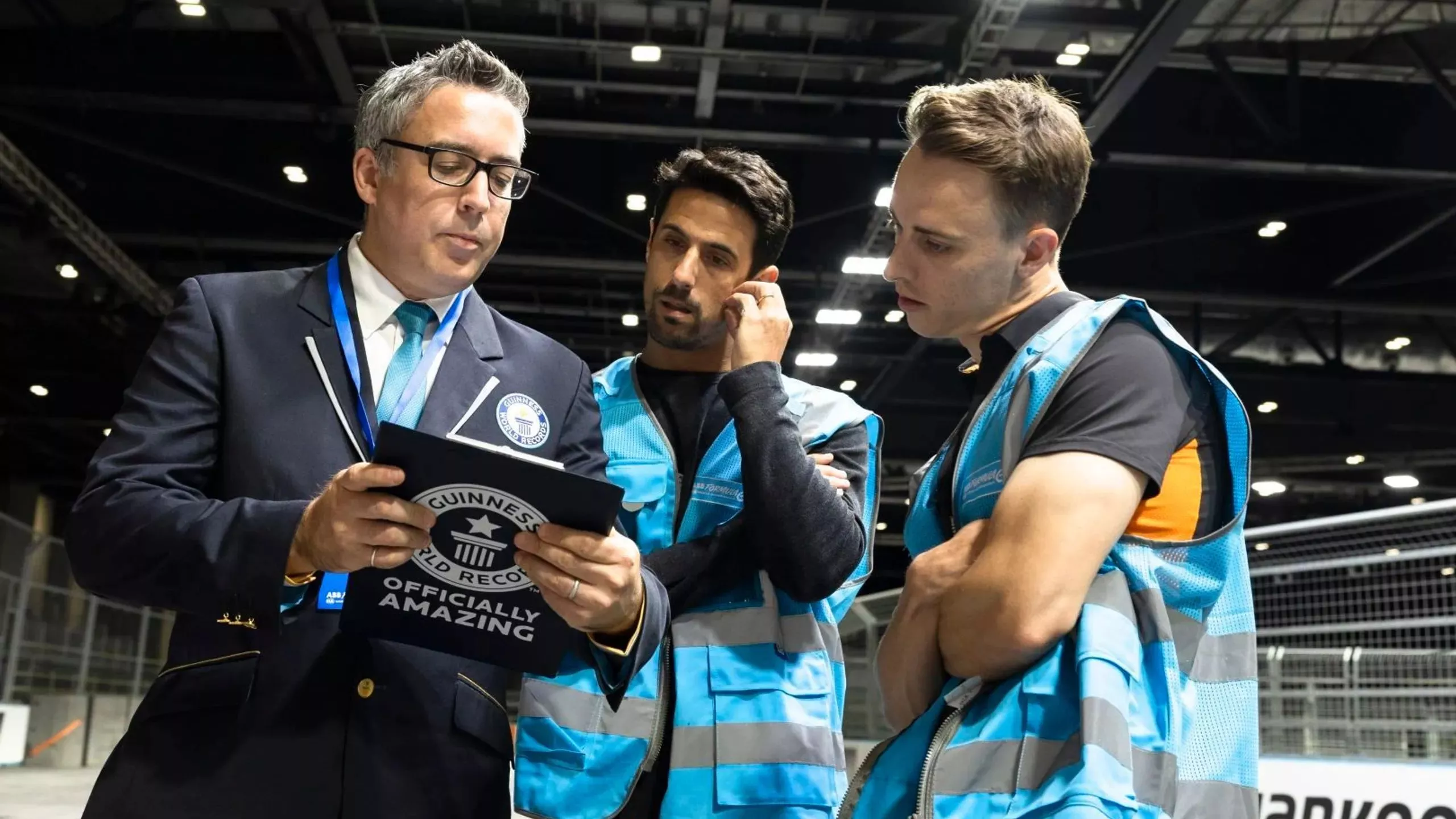 Jake Hughes (right) and Lucas di Grassi (center) raced head-to-head in a format used in Formula E for qualifiers, pictured here with an official from Guinness World Records