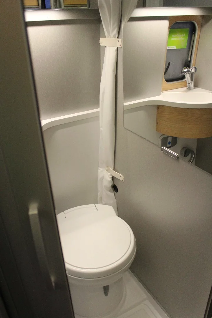 The bathroom includes a tambour door and a shower curtain that keeps the toilet, sink and mirror from getting wet