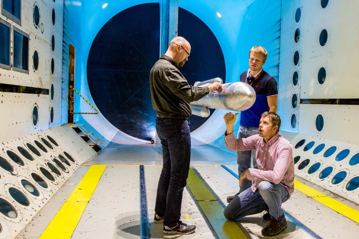 NASA engineers adjust a 10 ft model of the SLS rocket prior to aerodynamic testing