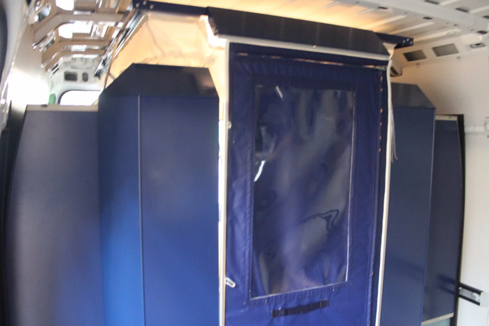 A roll-out fabric door covers the front end of the PlugVan camper