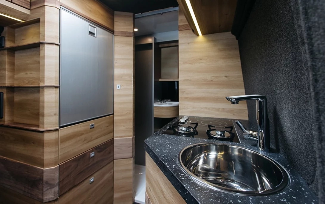 The kitchen area spans across the aisle and includes an oven/broiler, three-burner cooktop, sink and fridge/freezer