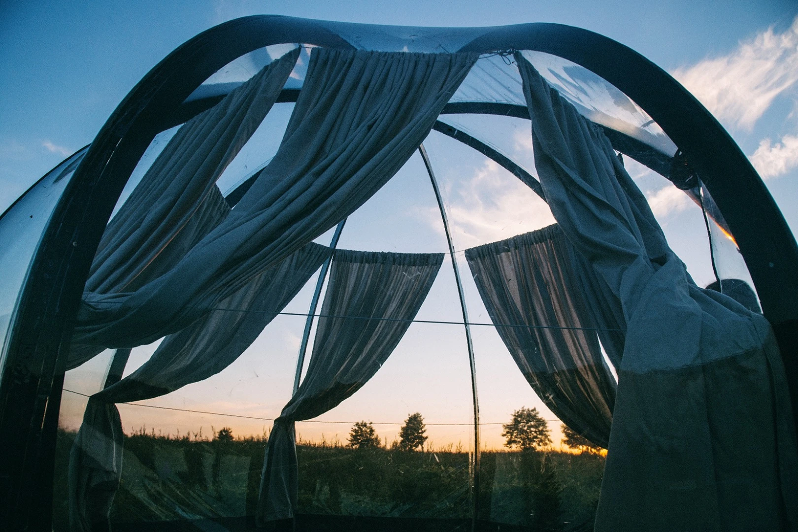 The Oasis dome tent features a tall curved framework with a clear exterior shell, offering users 360 degree views of the surrounding landscape