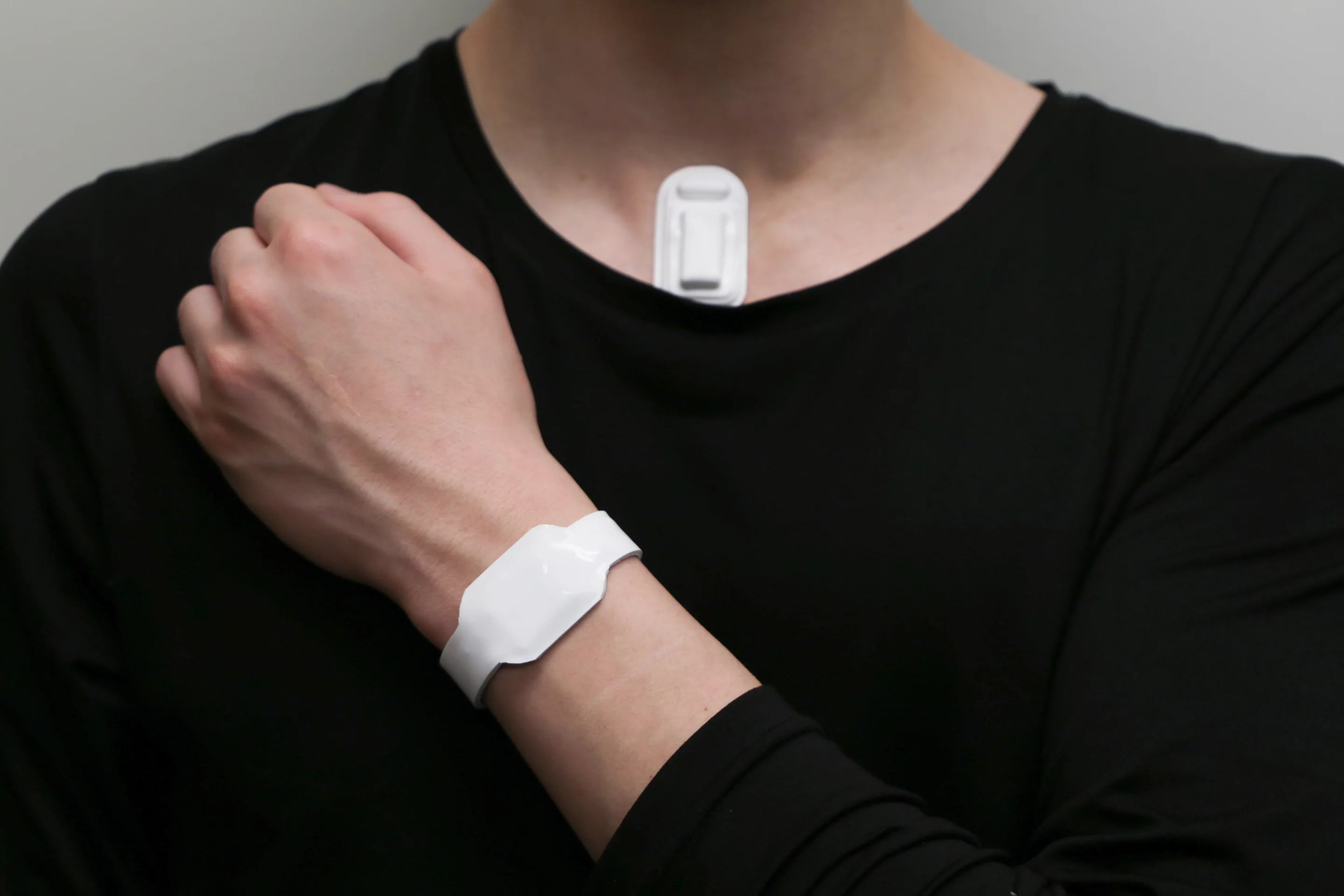 The system incorporates a vibrational sensor (chest) and a haptic feedback unit (wrist)