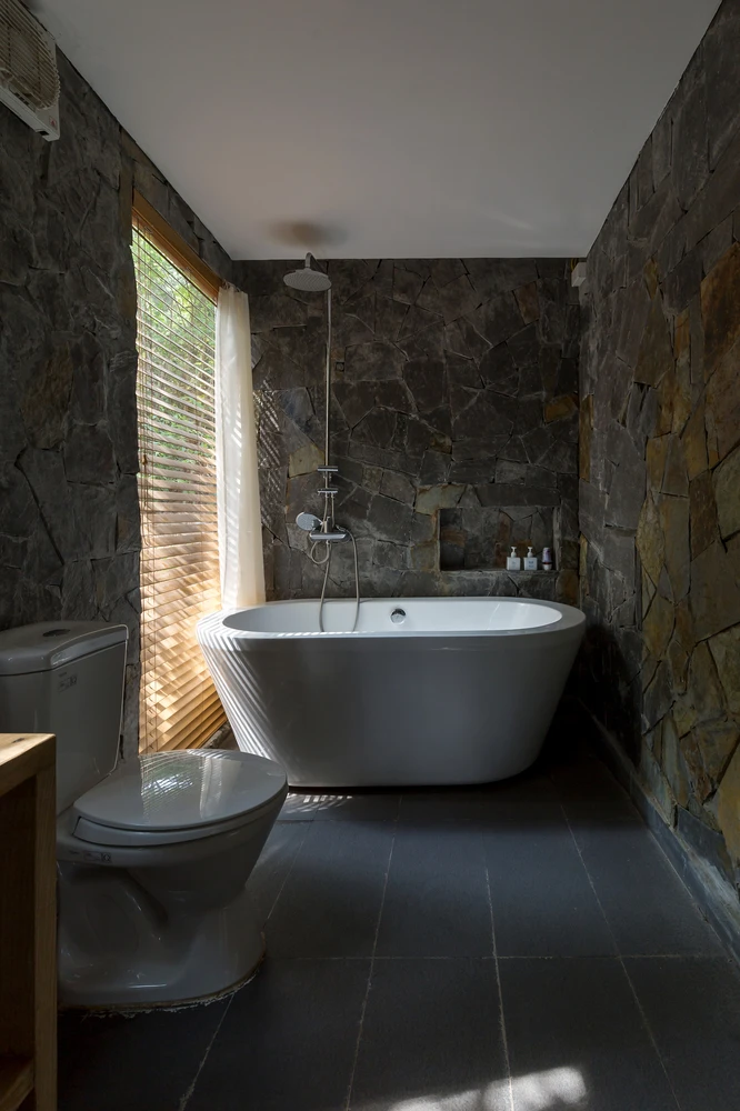 The gorgeous Forest House 02 bathroom with stone walls and natural light