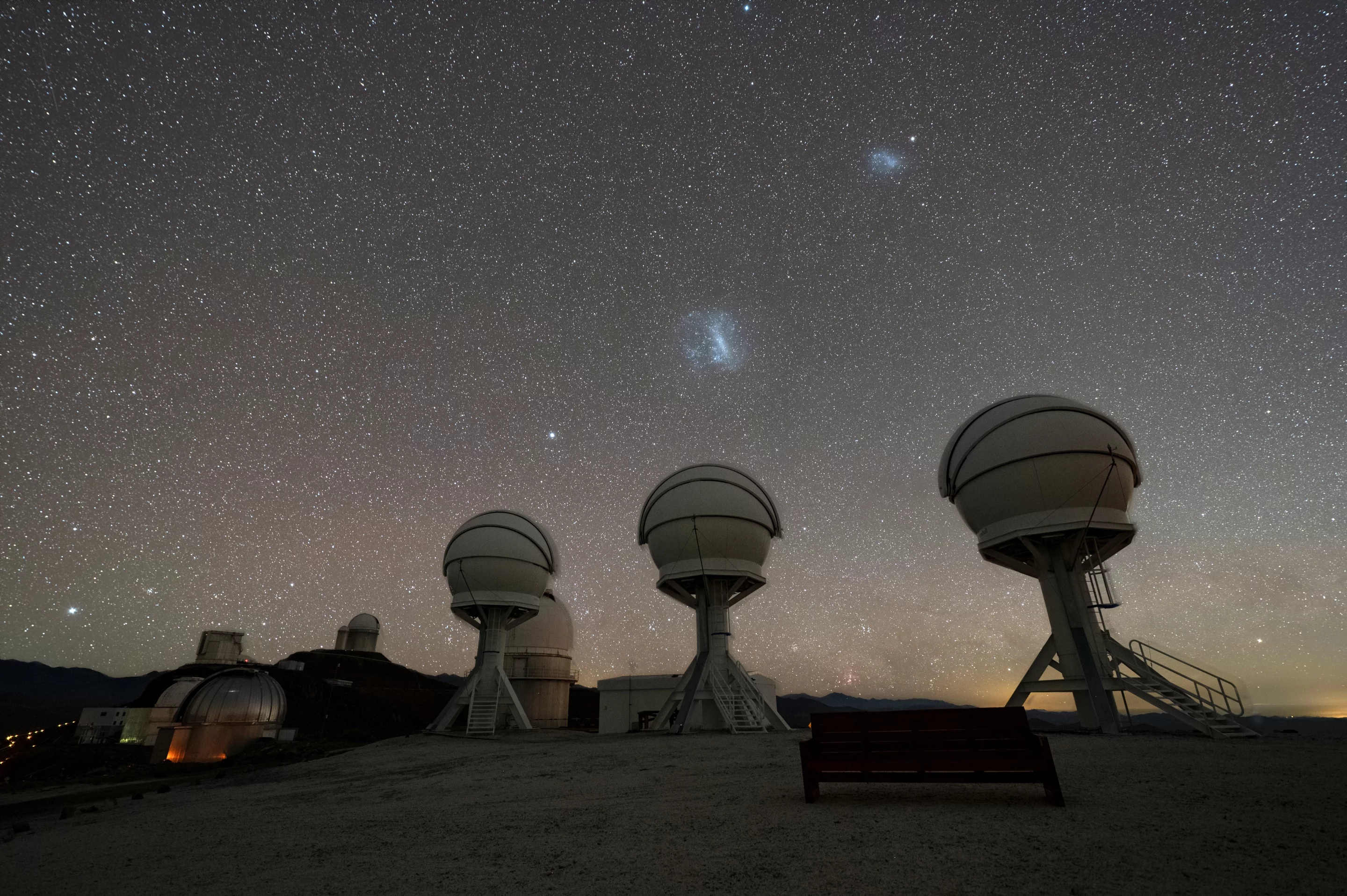 Shown in this nighttime image are the three telescopes of the BlackGEM array at ESO’s La Silla Observatory in Chile. The Large and Small Magellanic Clouds can be seen just above the telescopes. The BlackGEM array can quickly scan large areas of the sky to find a source that has emitted gravitational waves detected by LIGO and Virgo.