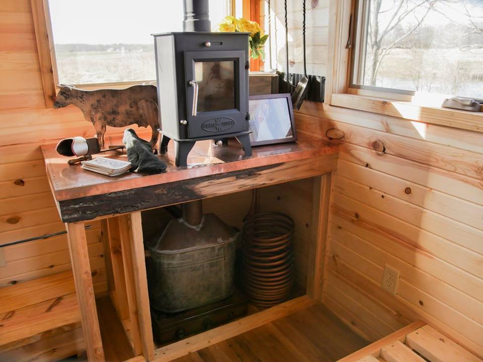 The Honey on the Rock's living room features a small wood-burning stove and a storage space for a heirloom whisky still