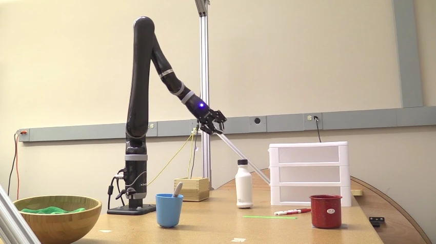 A robotic arm moves to pick up a felt pen