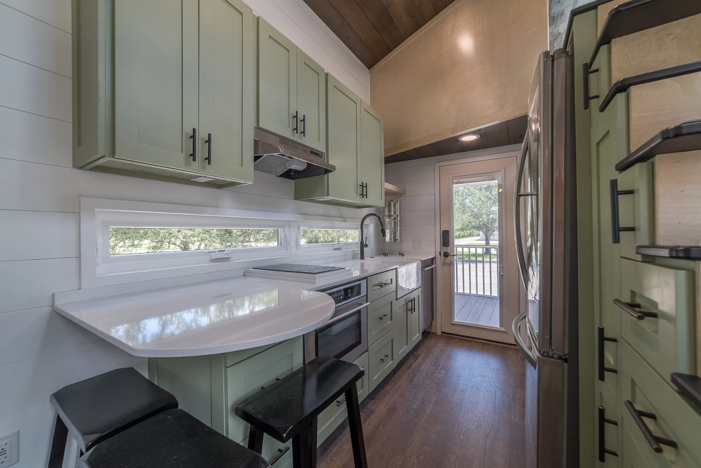 The kitchen is quite exquisite with an oven, countertop induction stove, and a full-size fridge and ample storage. It even features a three person bar at the end of the countertop.