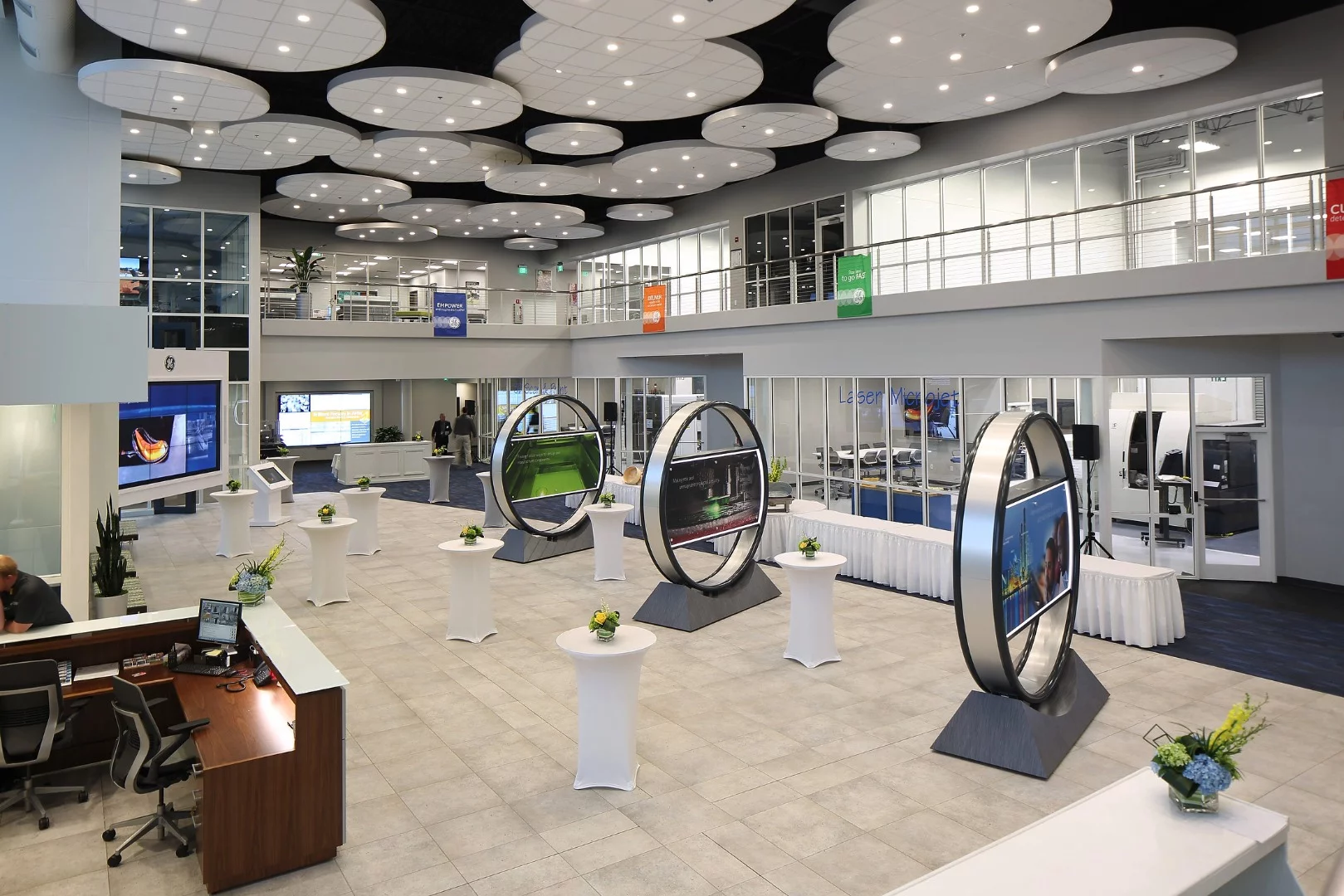 The futuristic, minimalist, lobby of the new facility features TV screens set in circles, while a wall of glass shows engineers busy on cutting-edge projects