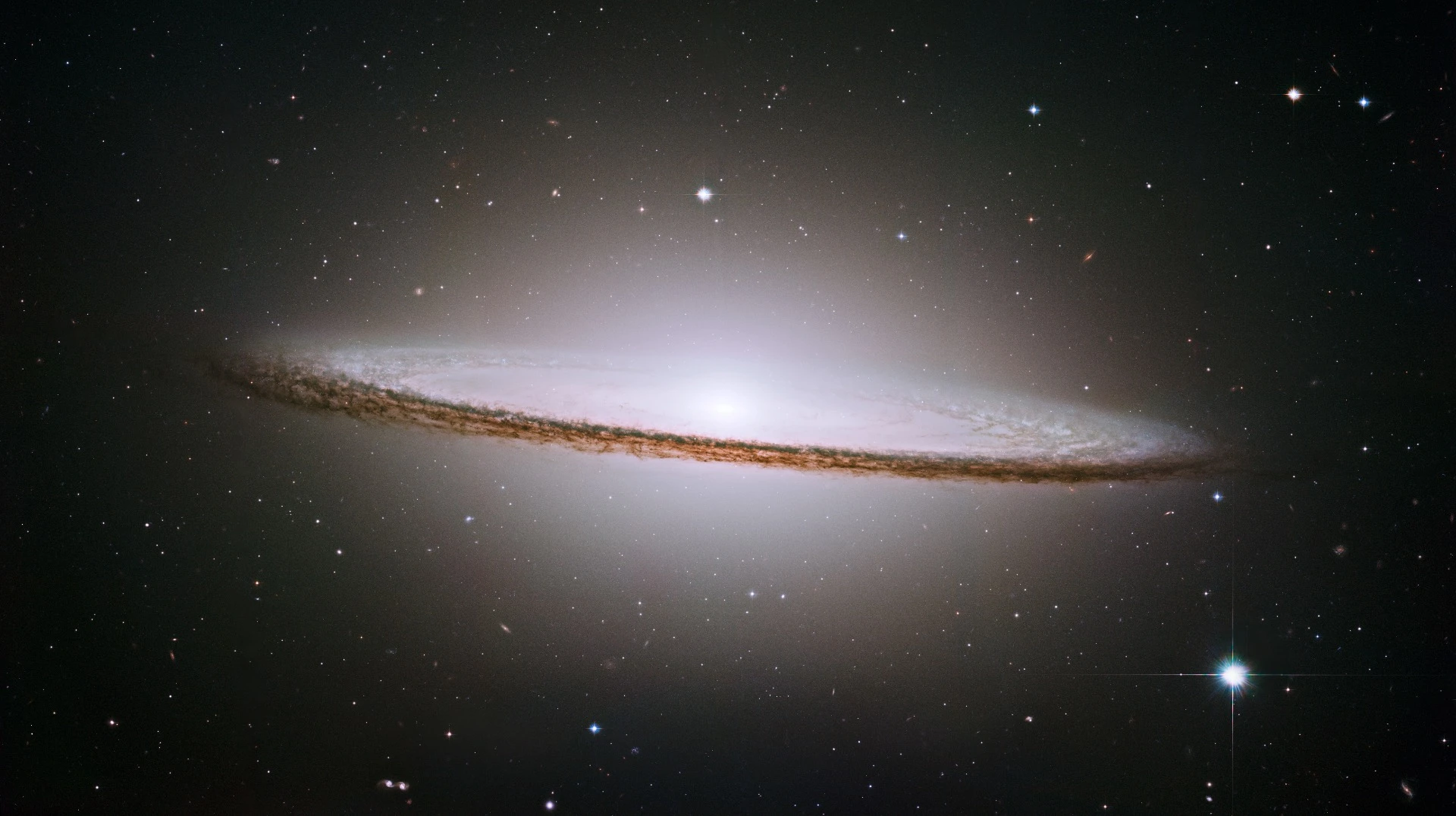 The Sombrero galaxy, Messier 104 (M104). The galaxy's hallmark is a brilliant white, bulbous core encircled by the thick dust lanes comprising the spiral structure of the galaxy. As seen from Earth, the galaxy is tilted nearly edge-on