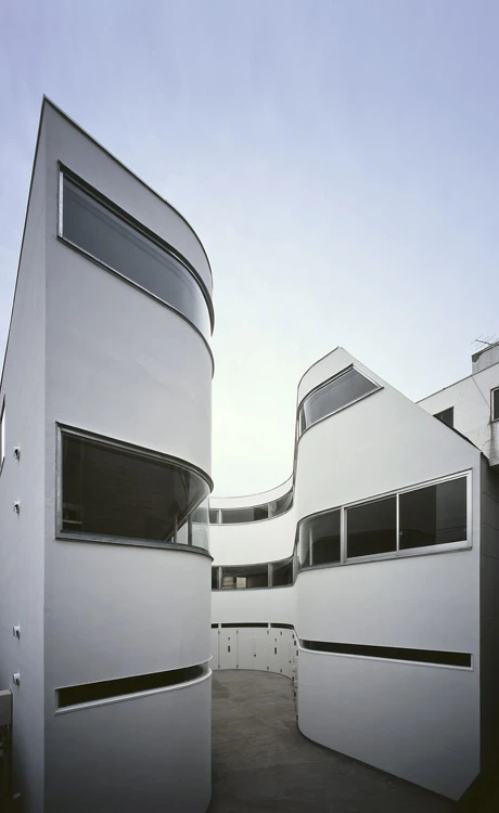 The C-shaped block, named NE apartments, envelops a central courtyard, optimally shaped for the greatest apartment volume while providing a sufficient turning circle for motorbikes