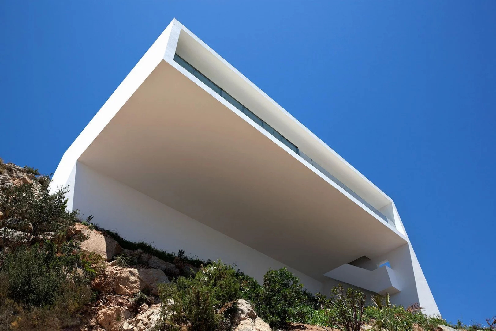 Another impressive cantilevered structure, this white modernist masterpiece from Fran Silvestre Arquitectos is on the coast of Spain facing the Balearic Sea. The clean white concrete building juxtaposes against the craggy grey landscape