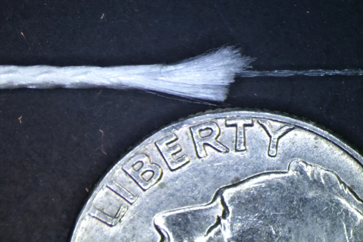 A sample of fiber optic fishing line with the inner fiber optic core exposed – the outer diameter of the fishing line is less than one millimeter