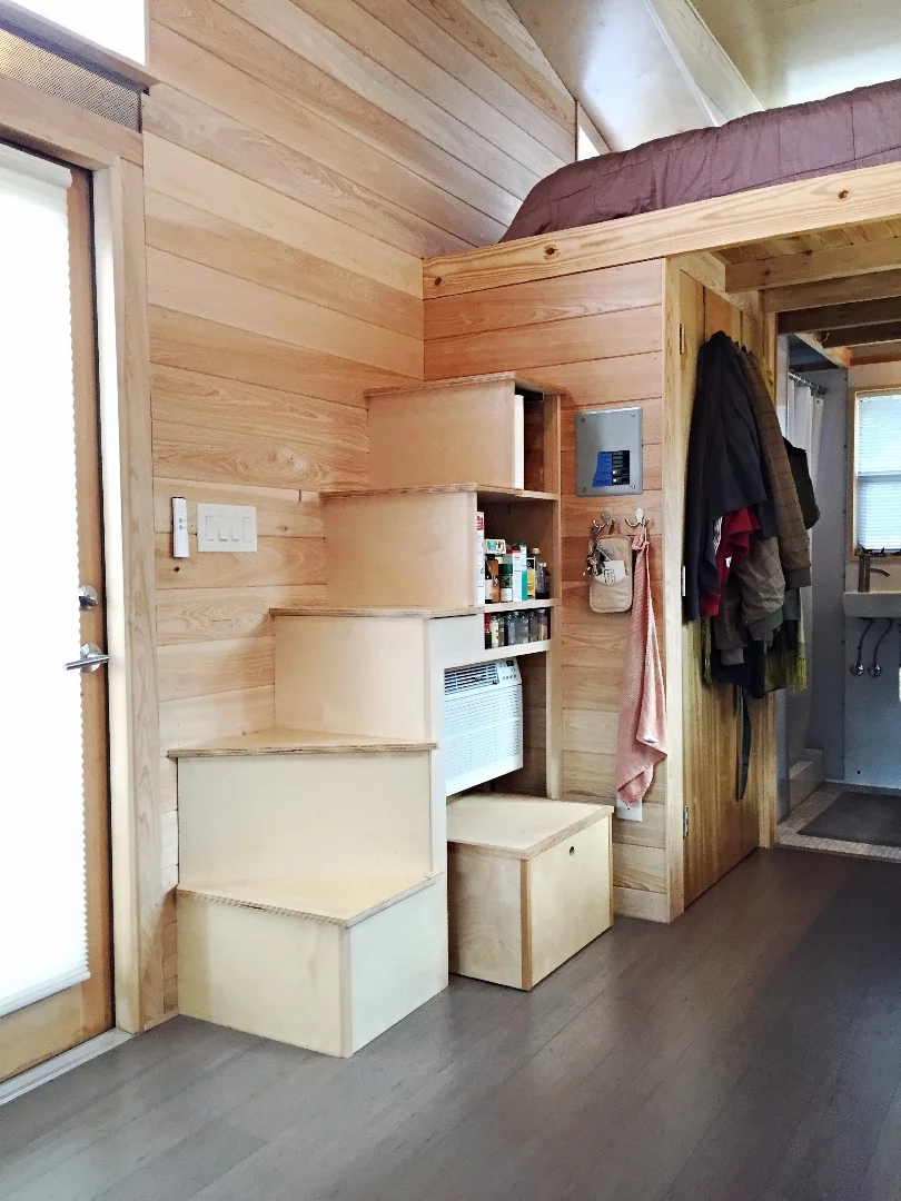 The upstairs sleeping area is reached via stairs that double as storage space