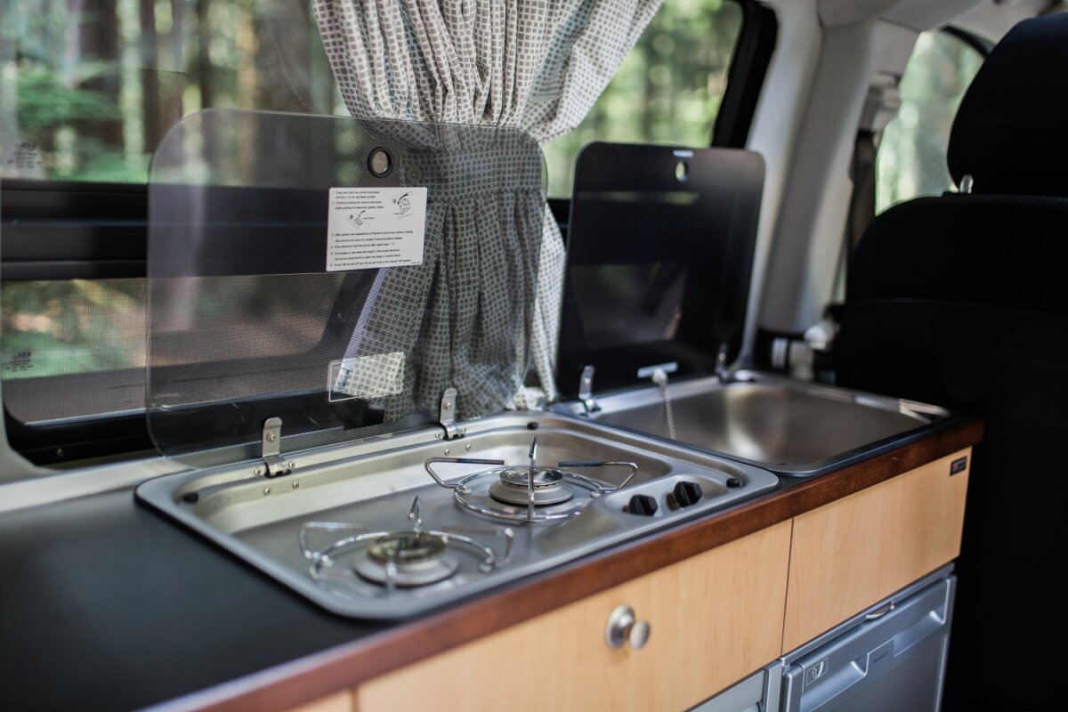 The kitchen area is compact but ready to cook, offering a dual-burner stove, sink and fridge