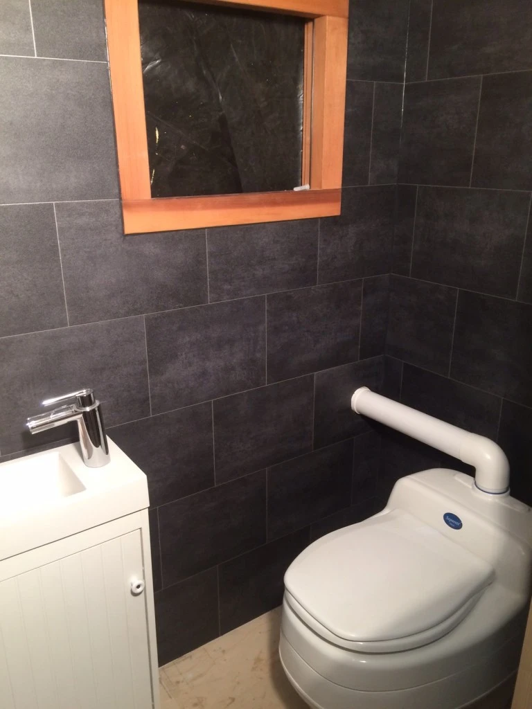 The bathroom includes a composting toilet, sink, and small shower
