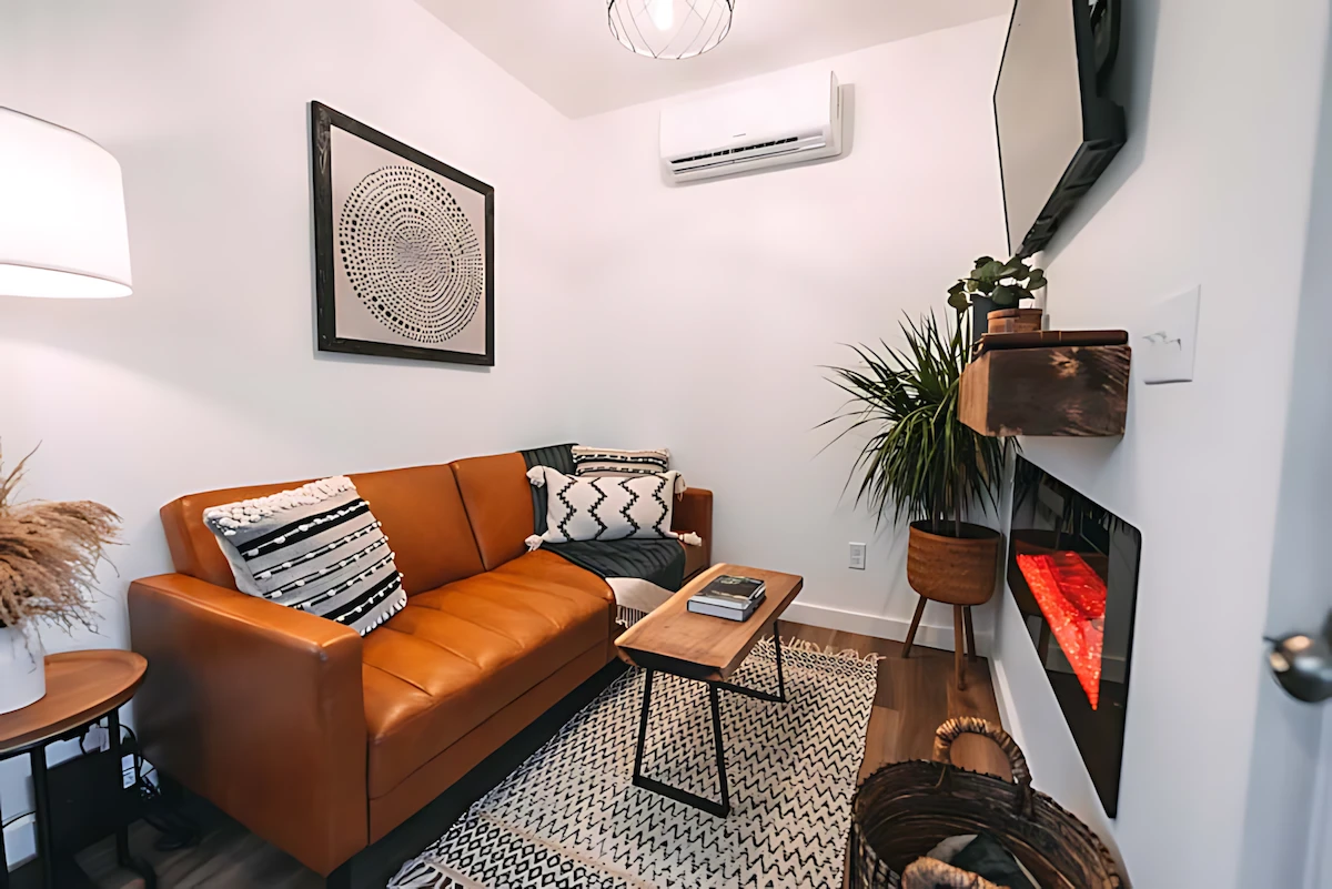 The Luna Cottage's living room features a sofa, a coffee table, an electric fireplace, and a mini-split air-con unit