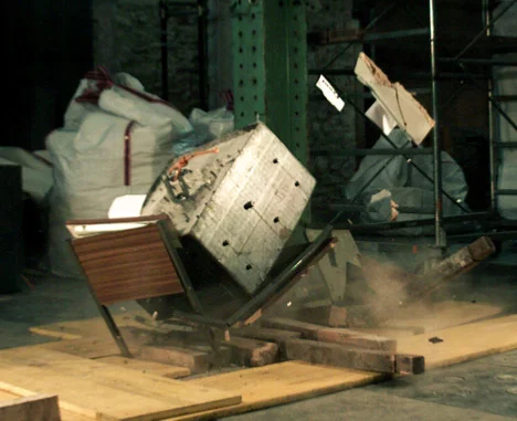 While it might block a few pieces of stray drywall and glass, a wooden desk isn't going to withstand the crushing weight from large chunks of concrete or steel