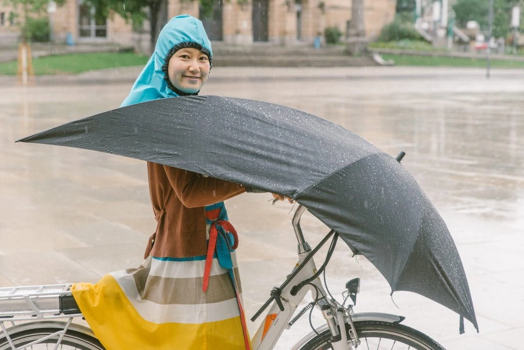 The user's head goes up through a collar tube built into the umbrella, and into an integrated waterproof hood