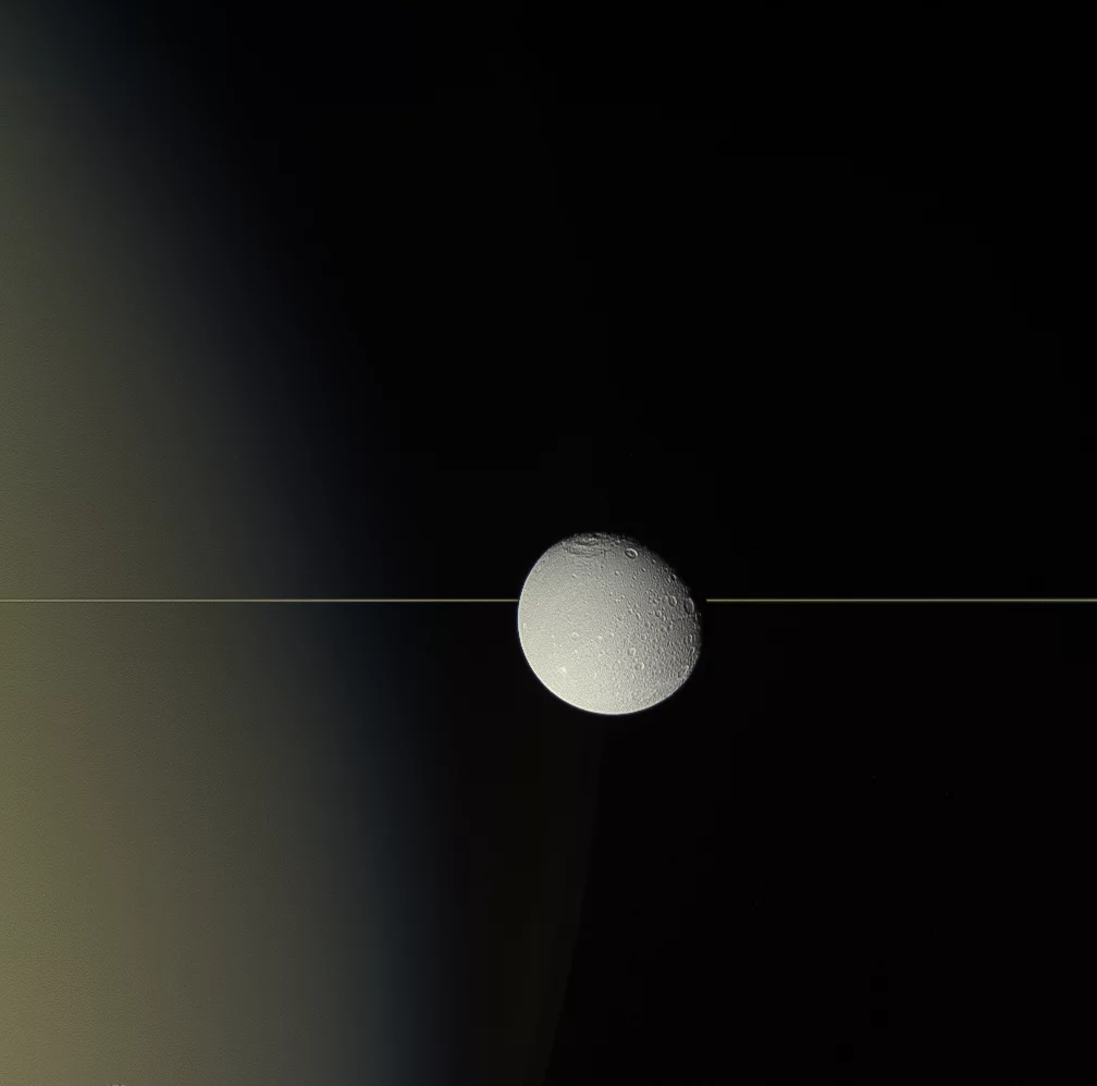 Saturn's moon Dione drifts in front of the planet's iconic rings