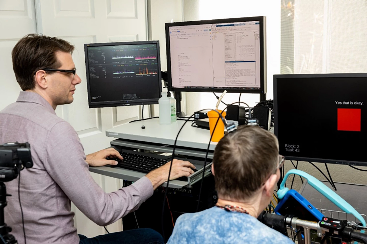 A Stanford Medicine researcher operates software that translates Pat's attempts at speech, recorded by sensors in her brain, into words on a screen