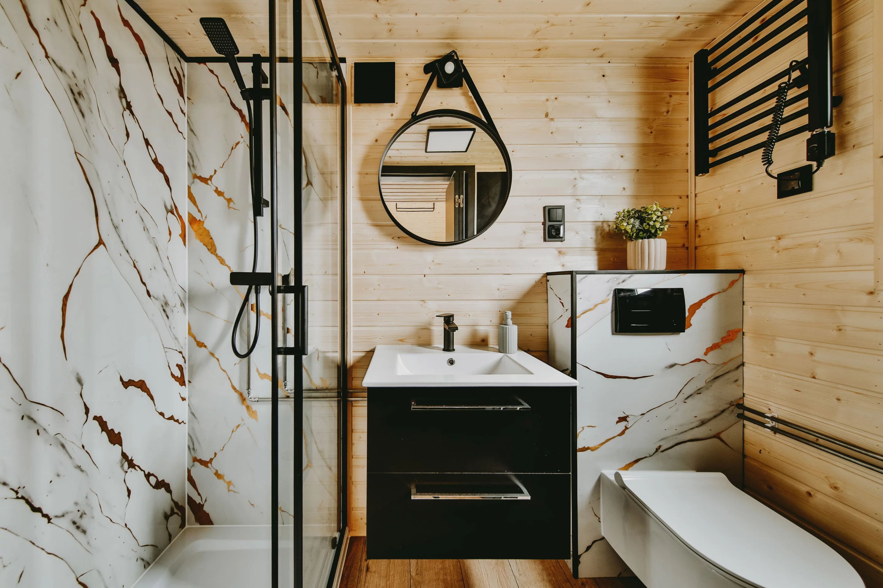 The Alan's bathroom contains a glass-enclosed shower, a vanity sink, and a flushing toilet