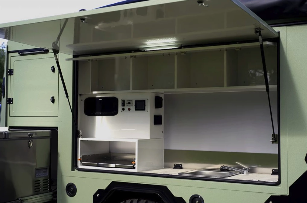 The kitchen has upper cabinets, a stove slide-out, hookups, a sink, and a large fridge/work slide-out