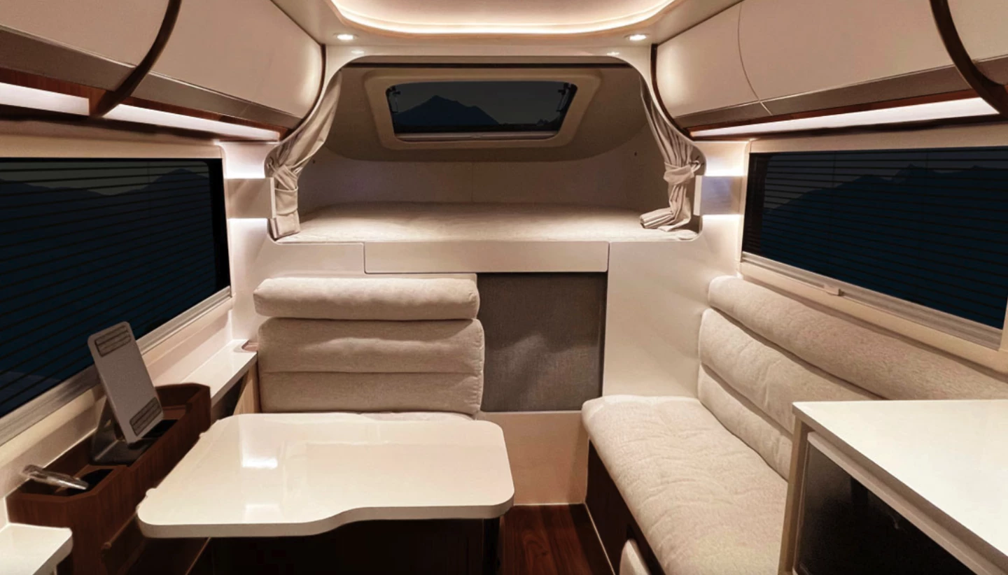 Looking forward from the entryway, the entrant can see the dinette on the left, the alcove bed straight ahead up high, and the side-facing sofa on the right