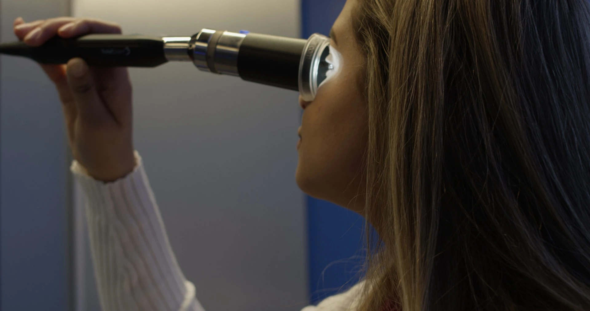 A patient holds the camera up to her eye to allow the doctor to see it close-up through the OnMed Station