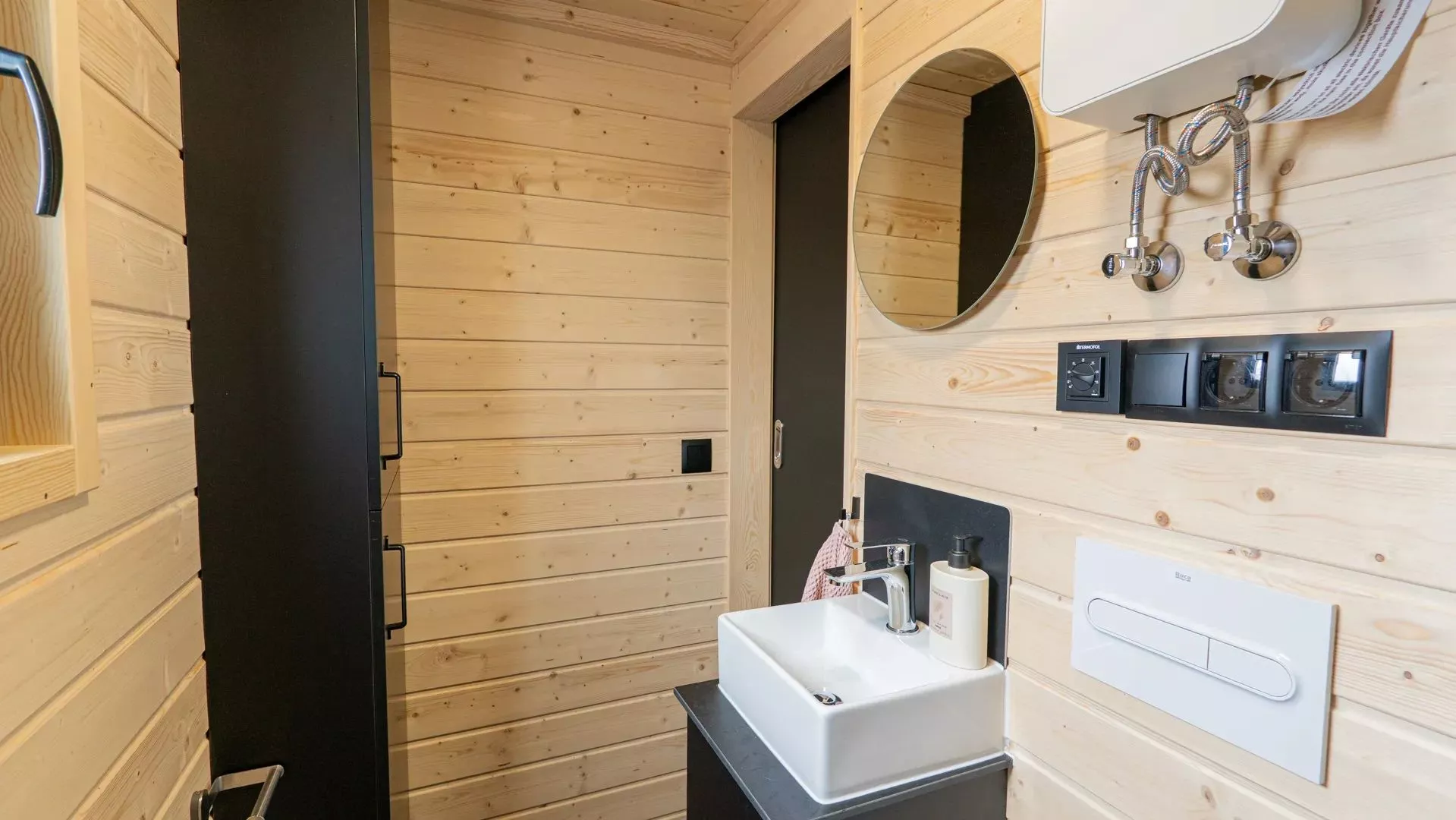The bathroom is accessed by a sliding door, is where the boiler is mounted, and benefits from cabinets for storage
